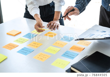 Two creative business people meeting and planning use note on desk to share idea, Analysis data chart and graph with teamwork strategy brainstorming in office 76844505