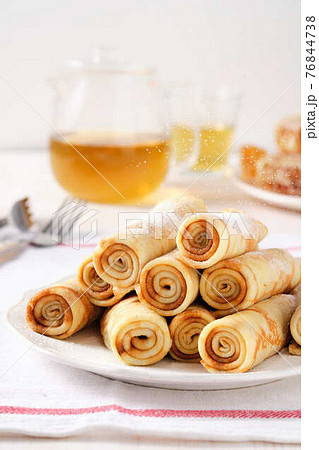 Crepes, thin pancakes with honey and tea on a white plate. 76844738