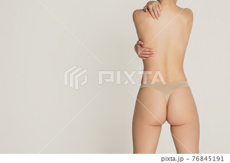 Beautiful female body in nude color underwear over grey background. 76845191
