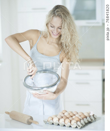 Happy woman mixing cookie batter in kitchen at counter Happy woman mixing cookie batter in kitchen at counter 76845820