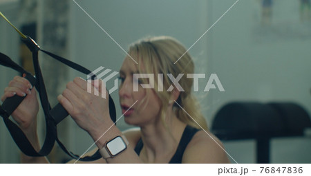 Closeup fit woman trains with trx resistance system in a modern gym. Healthy lifestyle. 76847836