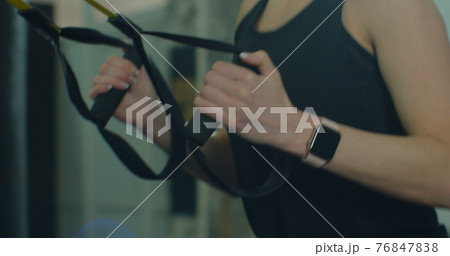 Closeup fit woman trains with trx resistance system in a modern gym. Healthy lifestyle. 76847838