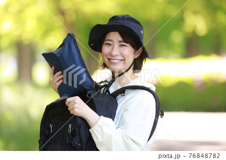 リュックサックから雨具を取り出す女性 76848782