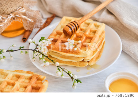 Honey pouring on a fresh Belgian waffles. Honey pouring on a fresh Belgian waffles. 76851890