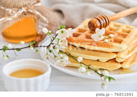 Honey pouring on a fresh Belgian waffles. Honey pouring on a fresh Belgian waffles. 76851891