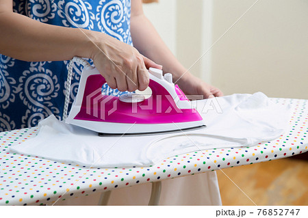 woman ironing white t-shirt with steam iron 76852747