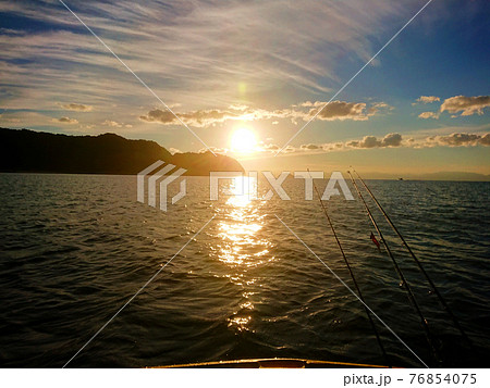 海の向こうから昇る朝日と釣り竿のシルエット 海の向こうから昇る朝日と釣り竿のシルエット 76854075