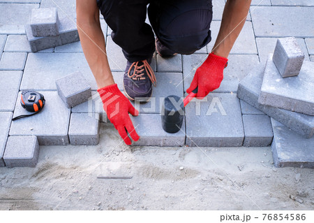 The master in yellow gloves lays paving stones 76854586