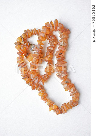 Yellow beautiful amber beads on a white background Yellow beautiful amber beads on a white background 76855162