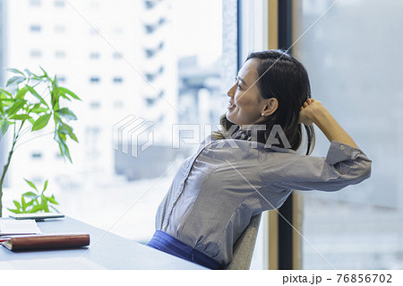 デスクで伸びをする女性 ビジネスシーン 76856702