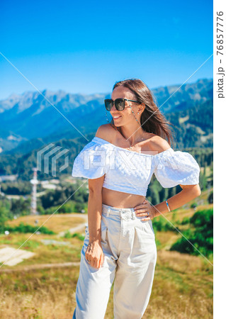 Beautiful happy young woman in mountains in the background of fog 76857776