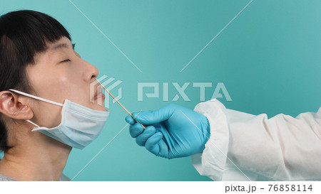Covid 19 swab test. woman with PCR test. Coronavirus test during epidemic. Medic taking sample for virus testing. studio shot and blue green background. Doctor in PPE suit swab testing. 76858114