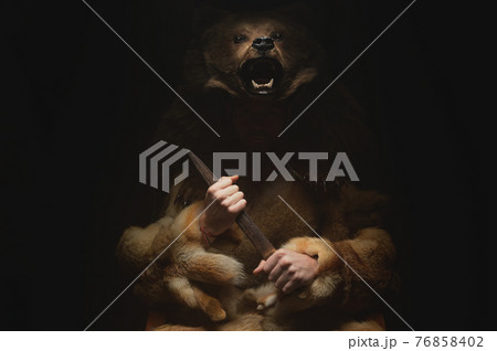 Low key portrait of a bearded war shaman in bearskin with an ancient ax in his hands. High quality cosplay of the ancient werewolf war 76858402