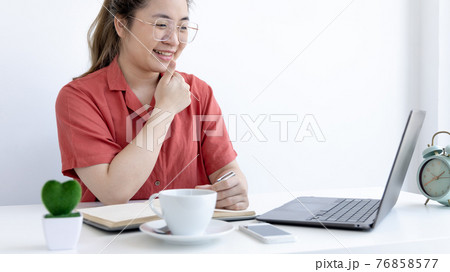 Asian business woman in a bright t-shirt is working at home, Stay home, New normal, Covid-19 coronavirus, Social distancing, Coming up with ideas for work, Writing information in a notebook. 76858577