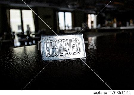 Metal plaque Reserved on a black table in a cafe against a background of blur and light in the windows. 76861476