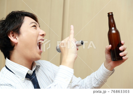 仕事帰りにカラオケを楽しむビジネスマンの男性 76863303