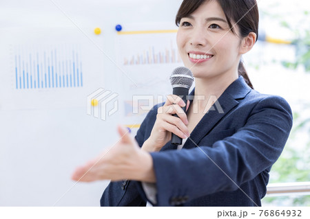 ビジネス　マイクを持ってプレゼンする女性 76864932