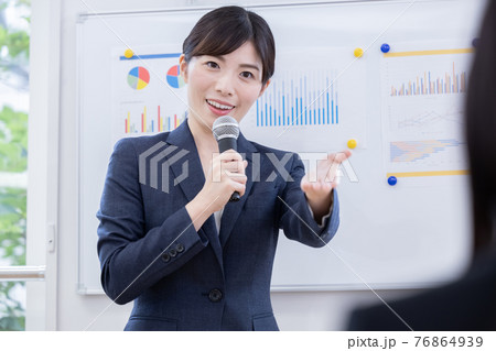ビジネス　マイクを持ってプレゼンする女性 76864939