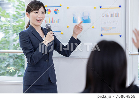 ビジネス　マイクを持ってプレゼンする女性 76864959
