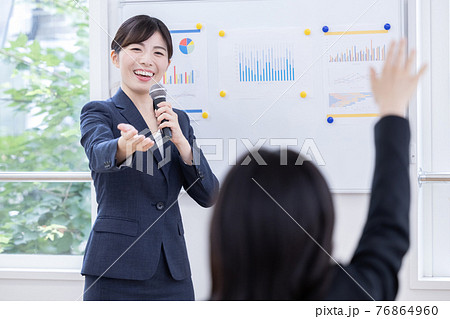 ビジネス　マイクを持ってプレゼンする女性 76864960