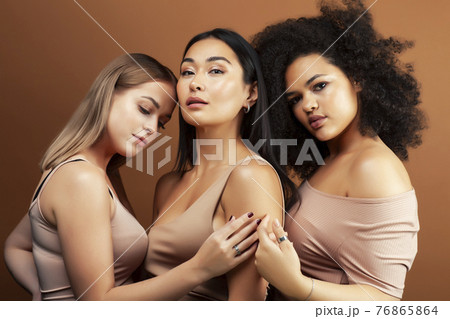 young pretty asian, caucasian, afro woman posing cheerful together on brown background, lifestyle diverse nationality people concept young pretty asian, caucasian, afro woman posing cheerful together on brown background, lifestyle diverse nationality people concept 76865864