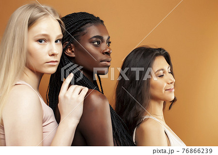 young pretty asian, caucasian, afro woman posing cheerful together on brown background, lifestyle diverse nationality people concept 76866239