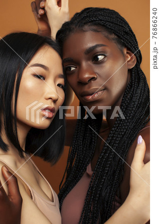 young pretty asian, afro woman posing cheerful together on brown background, lifestyle diverse nationality people concept 76866240