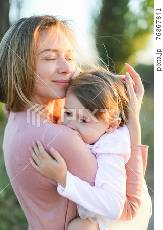 Portrait of young mother hugging little daughter and smiling. Portrait of young mother hugging little daughter and smiling. 76867841