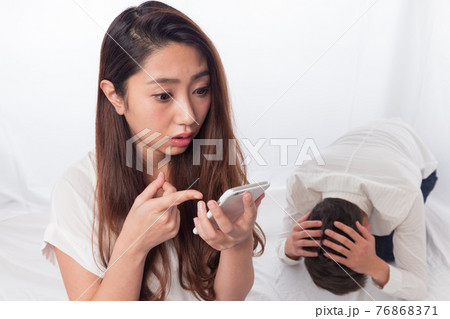 スマートフォンを持つ女性に頭を抱える男性 76868371