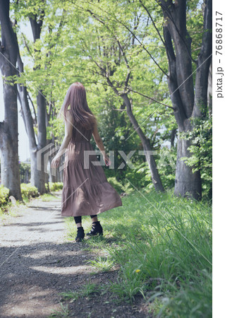 木々の小道を歩いて散歩する女性のポートレート 76868717