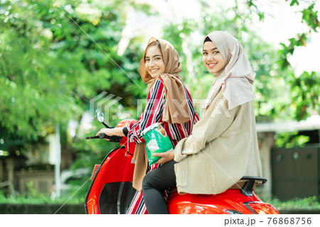 happy muslim girls riding scooter enjoy summer vacation 76868756