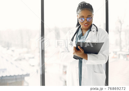 African doctor standing by window with a folder African doctor standing by window with a folder 76869272
