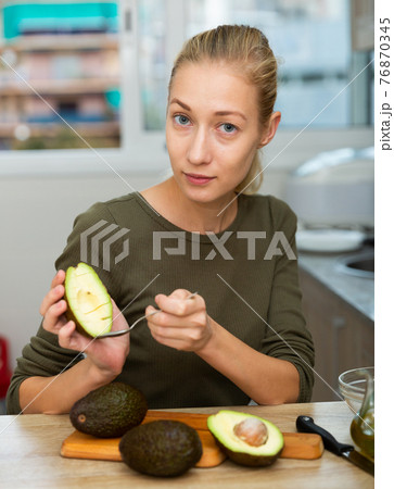 Happy housewife cooking with avocado at home kitchen 76870345
