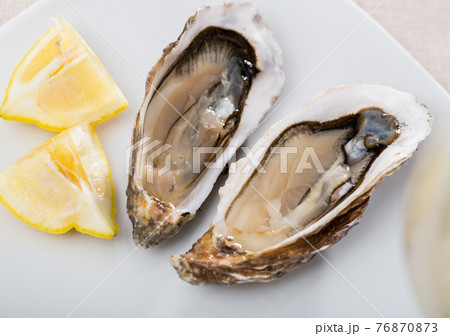 Tasty oysters with lemon on plate top view Tasty oysters with lemon on plate top view 76870873
