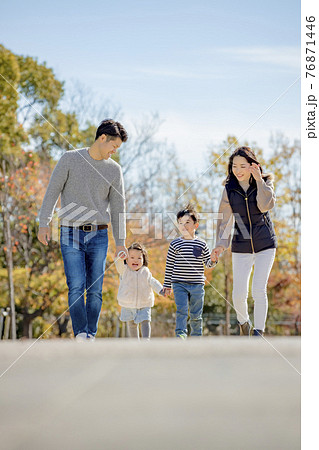 紅葉の公園を歩く4人家族 76871446