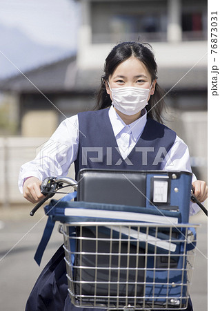 マスク姿で自転車に乗る中学生女の子 自転車通学イメージの写真素材