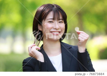 500円硬貨と箸を持つ女性社員　ワンコインランチイメージ 76873664