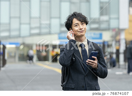 スマホを持つヘッドホンをした30代前半の男性 スマホを持つヘッドホンをした30代前半の男性 76874107