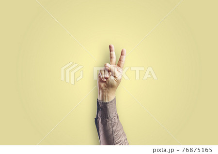 Man arm making victory gesture with hand isolated on yellow background 76875165