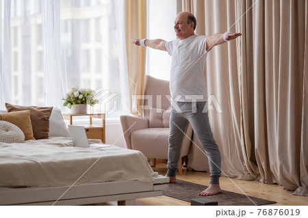 Portrait of a smiling senior man in sportswear standing at yoga asana Portrait of a smiling senior man in sportswear standing at yoga asana 76876019