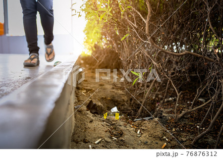 People throw trash on street beside the sidewalk,discarded garbage littered on the ground,dirty untidy with cigarette butts,rubbish littering in city public areas,pollution,environmental conservation 76876312