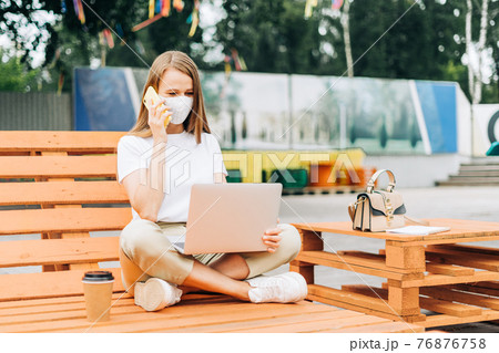 Business woman in medical face mask talking over the phone outdoors 76876758