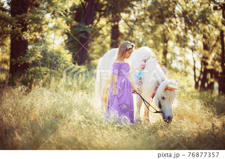Girl in purple dress hugging white unicorn horse. Dreams come tr 76877357