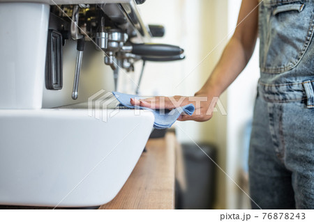 Womans hand with napkin sliding on coffeemaker Womans hand with napkin sliding on coffeemaker 76878243