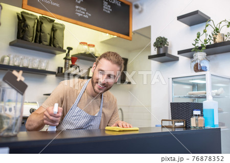 Smiling man carefully wiping surface of bar counter Smiling man carefully wiping surface of bar counter 76878352