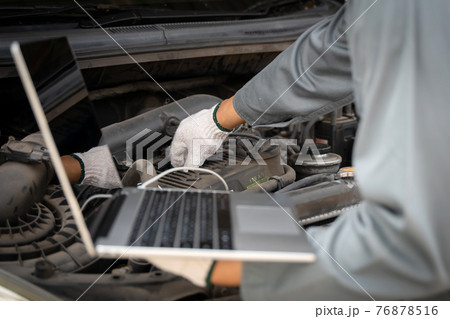 Mechanic using a laptop computer to check collect information during work a car engine. service maintenance of industrial to engine repair. Mechanic using a laptop computer to check collect information during work a car engine. service maintenance of industrial to engine repair. 76878516