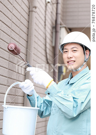 一軒家の外壁に塗装をする作業員の男性 一軒家の外壁に塗装をする作業員の男性 76878720