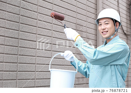 一軒家の外壁に塗装をする作業員の男性 一軒家の外壁に塗装をする作業員の男性 76878721