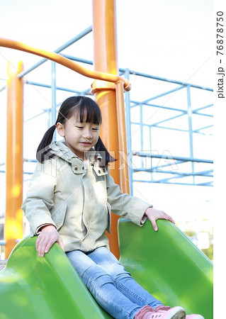 公園の滑り台で遊ぶ5歳の女の子の写真素材