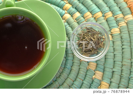 top view of green tea and herbal leaf in a small glass bowl on table  76878944